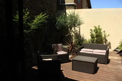 two wicker chairs and a table on a wooden deck at La Glycine Blanche in Pomas