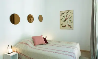 a white bedroom with a bed with a pink pillow at La Maison des Vendangeurs sur Mer in Gruissan