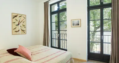 a bedroom with a bed and large windows at La Maison des Vendangeurs sur Mer in Gruissan