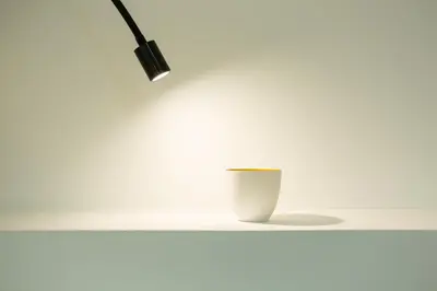a white table with a lamp and a cup on it at La Maison des Vendangeurs sur Mer in Gruissan