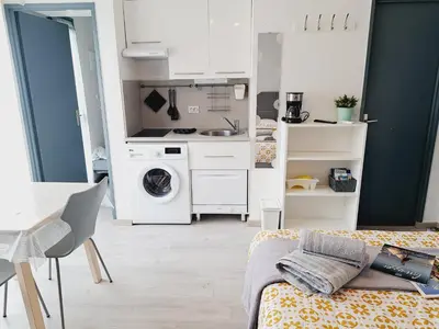 a small white kitchen with a washing machine in a room at Studio Moderne - Plage du Grazel in Gruissan