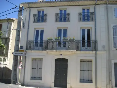 a white building with a door and a balcony at Gites de Gabrielle in Capestang