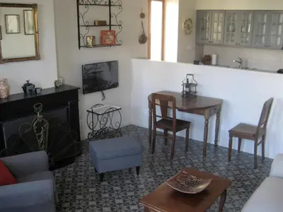 a living room with a table and a kitchen at Gites de Gabrielle in Capestang