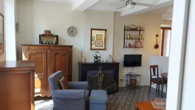 a living room with a blue chair and a fireplace at Gites de Gabrielle in Capestang