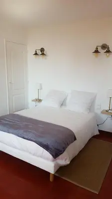 a bedroom with a large white bed with two lamps at Appartement au coeur de Carcassonne in Carcassonne