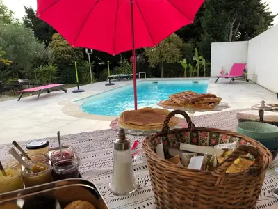 a picnic table with a red umbrella next to a pool at Aux Belles Vacances - ADULTS ONLY in Caux-et-Sauzens
