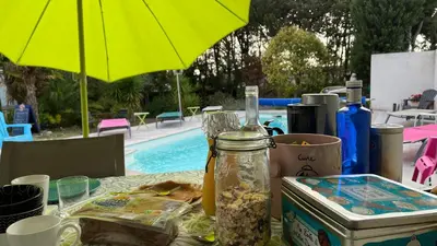 a table with food and an umbrella next to a pool at Aux Belles Vacances - ADULTS ONLY in Caux-et-Sauzens