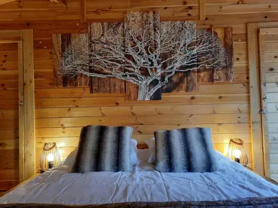 a bedroom with a bed with a tree on the wall at Domaine de la Vitarelle Glamping in Villanière