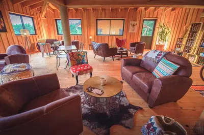 a living room with couches and chairs and a table at Domaine de la Vitarelle Glamping in Villanière