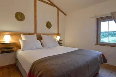 a bedroom with a bed with white pillows and a window at Domaine De Fraisse in Leuc