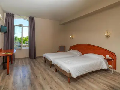 a bedroom with two beds and a desk and a window at Logis Hôtel restaurant Les Minotiers in Mirepoix