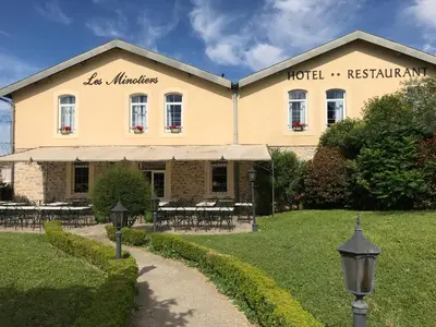 a building with tables and chairs in front of it at Logis Hôtel restaurant Les Minotiers in Mirepoix