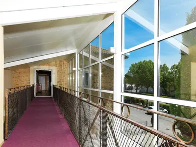 a walkway in a building with large windows at Logis Hôtel restaurant Les Minotiers in Mirepoix
