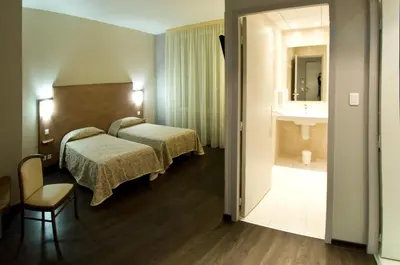 a hotel room with two beds and a bathroom at Logis Hôtel restaurant Les Minotiers in Mirepoix