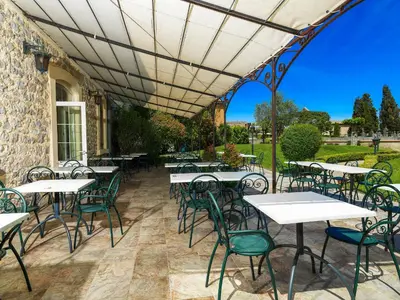 an outdoor patio with white tables and chairs at Logis Hôtel restaurant Les Minotiers in Mirepoix