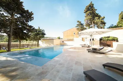a swimming pool with chairs and an umbrella at Château L'Hospitalet Wine Resort Beach & Spa in Narbonne