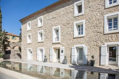 a stone building with white doors and a reflection at Château L'Hospitalet Wine Resort Beach & Spa in Narbonne