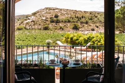 a table on a balcony with a view of a pool at Château L'Hospitalet Wine Resort Beach & Spa in Narbonne