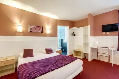 a hotel room with a bed and a desk at Hôtel Du Midi in Narbonne