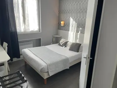 a small bedroom with a bed and a window at Hôtel Du Midi in Narbonne
