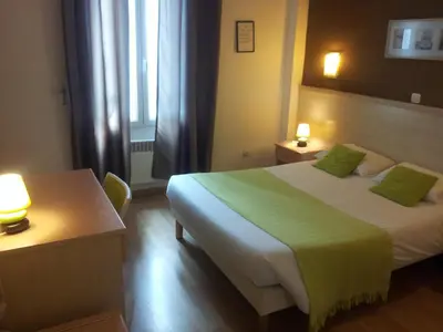 a hotel room with two beds and a window at Hôtel Du Midi in Narbonne