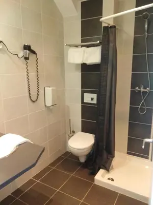 a bathroom with a toilet and a shower at Hôtel Du Midi in Narbonne