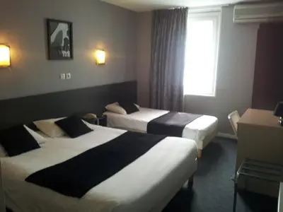 a hotel room with two beds and a window at Hôtel Du Midi in Narbonne