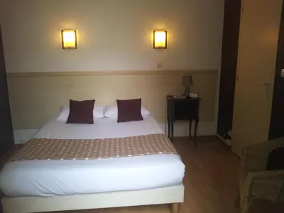 a bedroom with a bed with two pillows and a table at Hôtel Du Midi in Narbonne