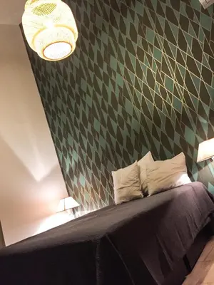 a bedroom with a bed with a green patterned wall at La Forge in Montséret