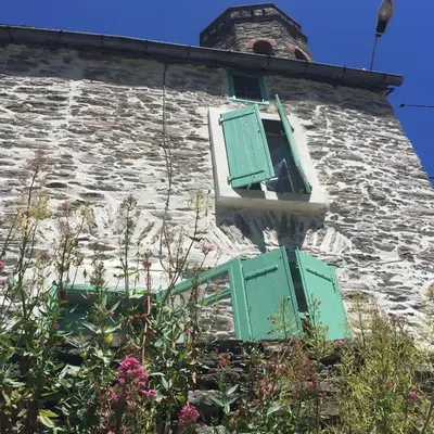 a stone building with green shuttered windows and flowers at Les Volets Verts in Miraval-Cabardès