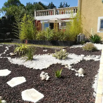 a garden with rocks and plants in front of a house at grand studio des rivages cathares in Carcassonne