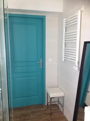 a blue door in a bathroom with a stool at grand studio des rivages cathares in Carcassonne