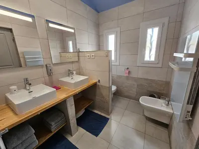 a bathroom with two sinks and a toilet and a mirror at La Casa del Arti - Hôtellerie & Spa - Centre bien-être et Piscine chauffée in Sigean