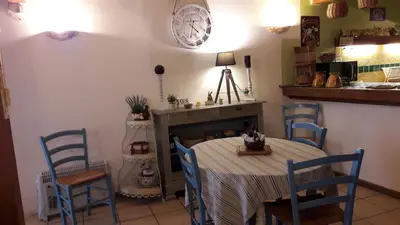 a dining room with a table and chairs and a clock at La Grange in Durban-Corbières