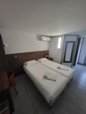 a bedroom with two beds with towels on them at Brit Hotel Plaisance A9/A61 in Narbonne