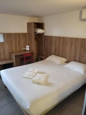 a large white bed with two folded towels on it at Brit Hotel Plaisance A9/A61 in Narbonne