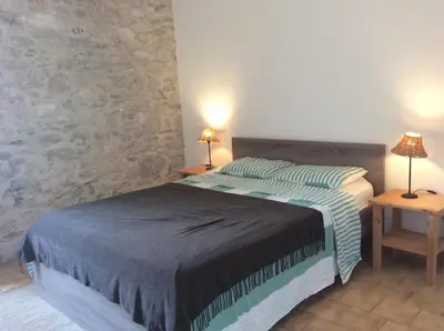 a bedroom with a bed and two lamps on two tables at Maison Ancienne Minervois in La Caunette