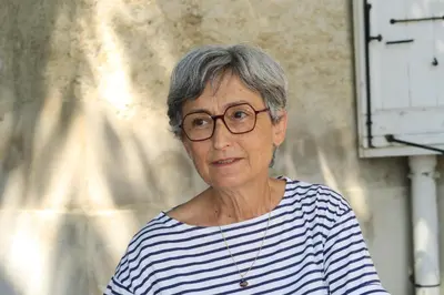 a woman wearing glasses standing in front of a building at La Lauze in Vielmur-sur-Agout