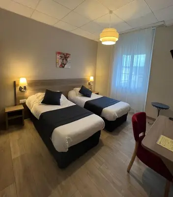 a hotel room with two beds and a table at Hôtel Le Roi Gourmand in Pamiers