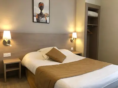 a bedroom with a large bed with two lamps at Hôtel Le Roi Gourmand in Pamiers