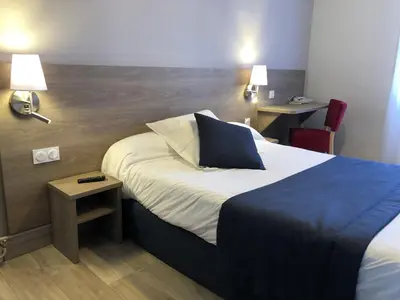 a hotel room with a bed and two tables at Hôtel Le Roi Gourmand in Pamiers