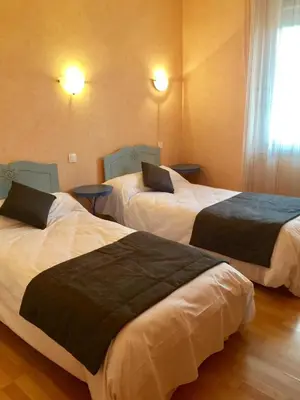 a hotel room with two beds and a window at Hôtel Le Roi Gourmand in Pamiers