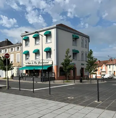 a white building with green awnings on a street at Hôtel Le Roi Gourmand in Pamiers