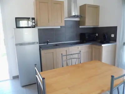 a kitchen with a wooden table and a white refrigerator at Le Logis de Liliana in Villemoustaussou