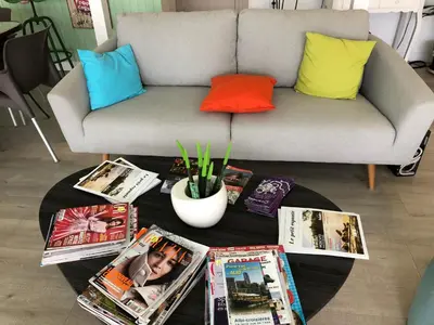 a living room with a couch and magazines on a table at Le 81 HOTEL in Castres