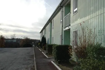 a green building with bushes next to a street at Le 81 HOTEL in Castres