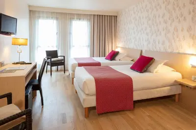 a hotel room with two beds and a desk at Hotel La Chaumière in Quillan
