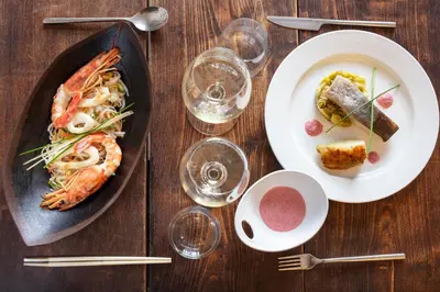a wooden table with plates of food and glasses of wine at Hotel La Chaumière in Quillan