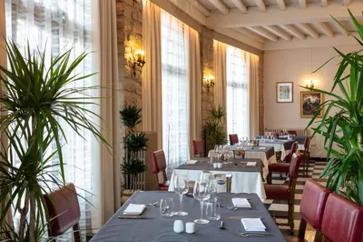 a restaurant with tables and chairs and plants at Hotel La Chaumière in Quillan