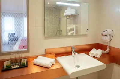 a bathroom with a sink and a mirror and towels at Hotel La Chaumière in Quillan